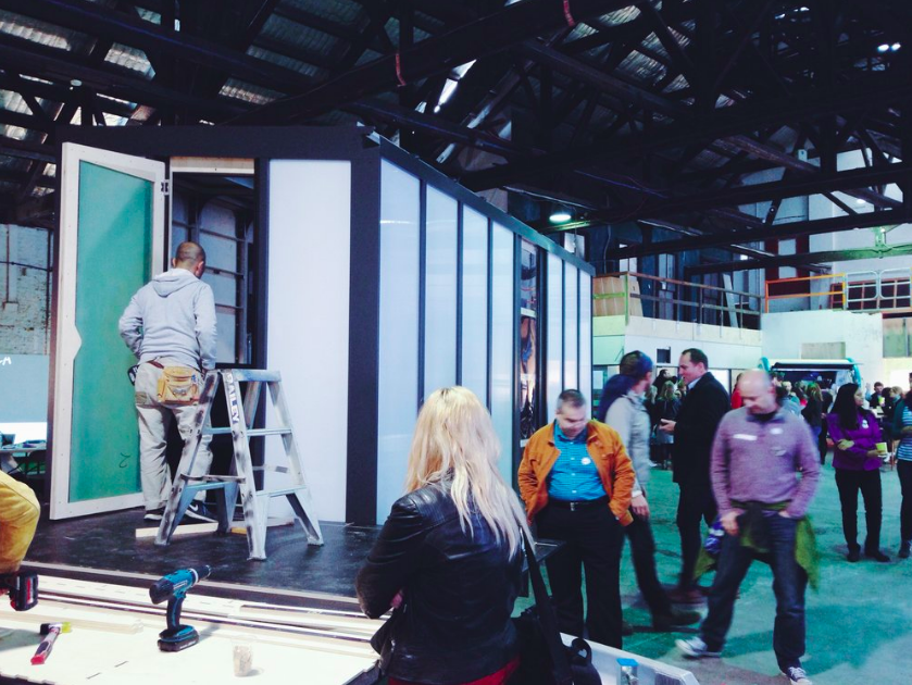 People gather around as the first tiny home prototype is built by volunteers inside the Commune in Waterloo. Photo credit: Luschia Porter